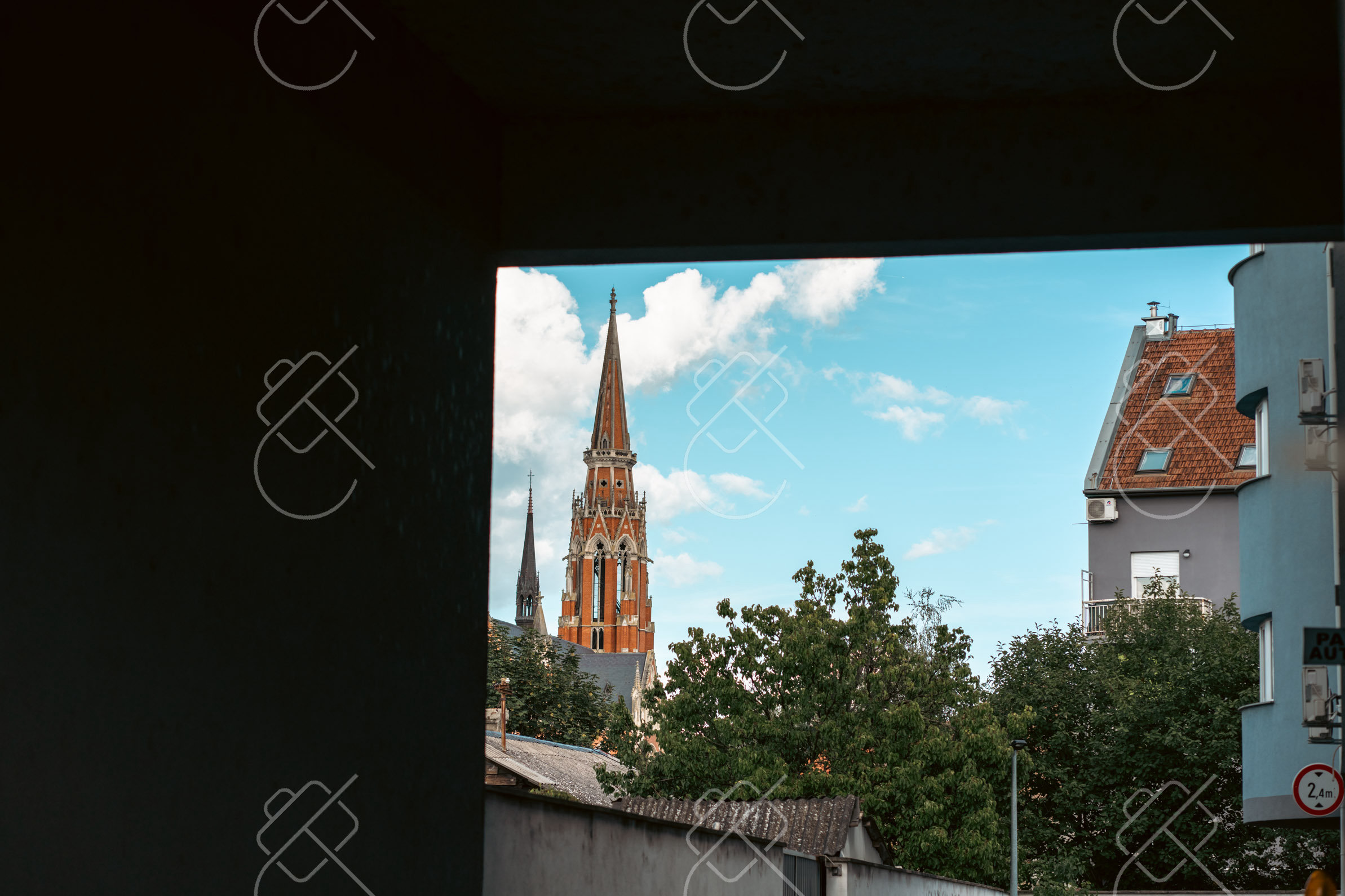 The cathedral's neo-Gothic spire framed through a doorway — Osijek, fine art travel photography print available from Clever Tourists