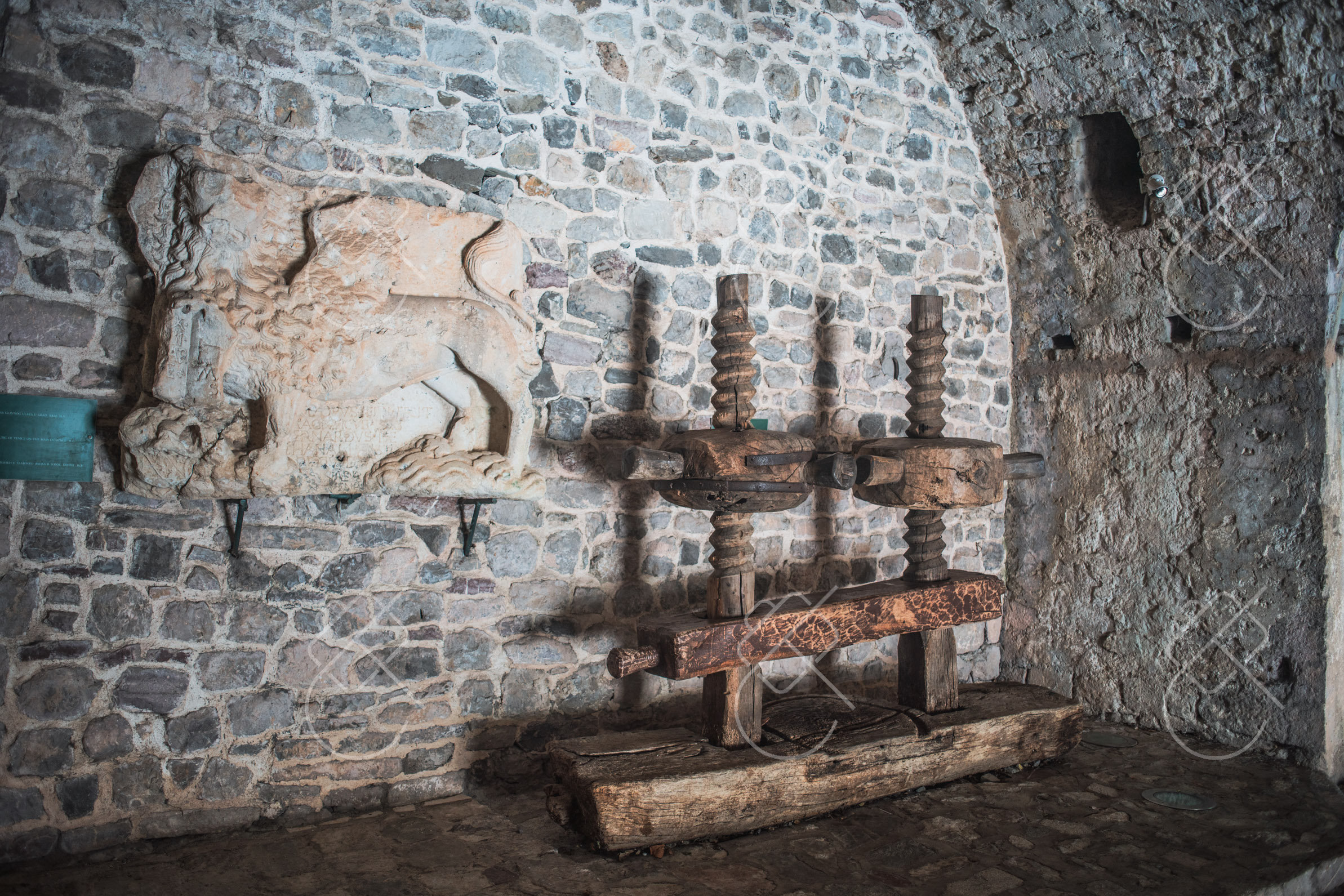 An old olive press inside the museum's stone-vaulted customs building — Stari Bar, fine art travel photography print available from Clever Tourists