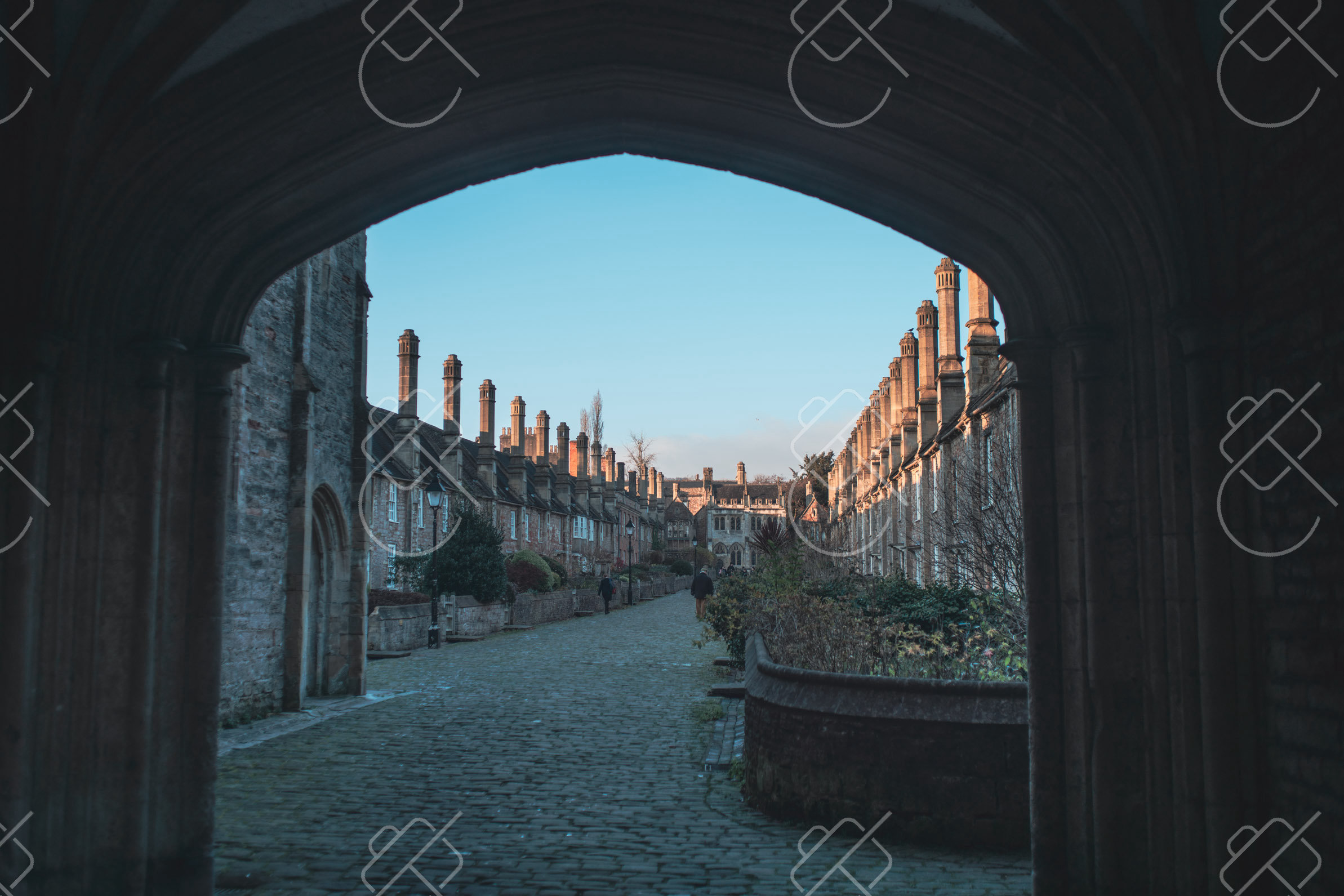 Vicars' Close and its row of tall chimneys, framed by the archway of the Chain Gate — Wells, fine art travel photography print available from Clever Tourists